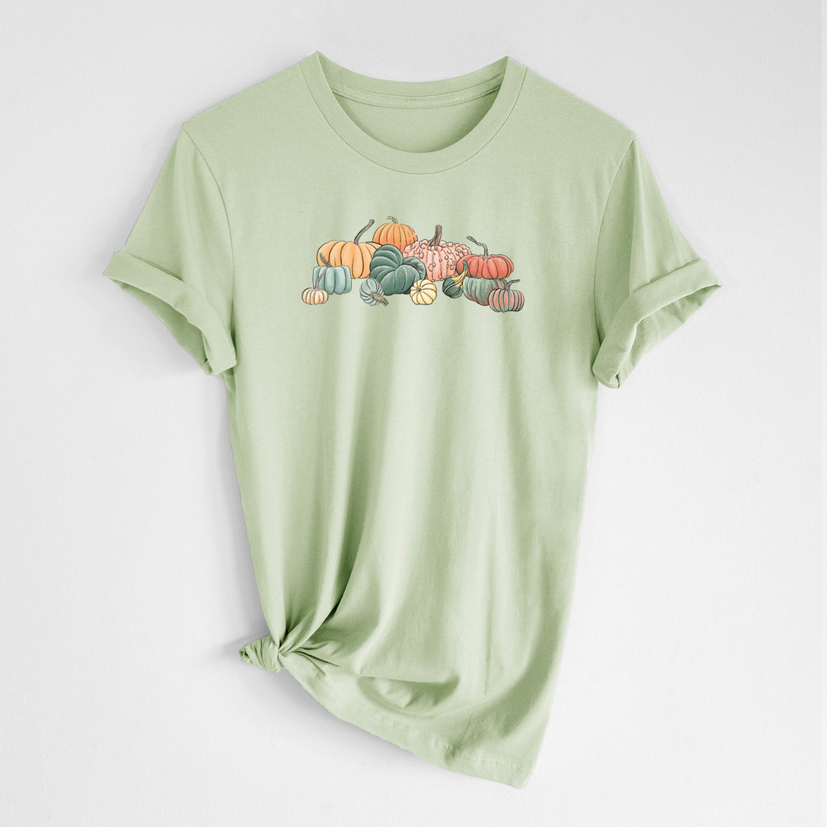 Spring green lightweight cotton t-shirt laid flat with the sleeves rolled, printed with a full-color illustration of a pile of pumpkins and gourds in orange, green and white.