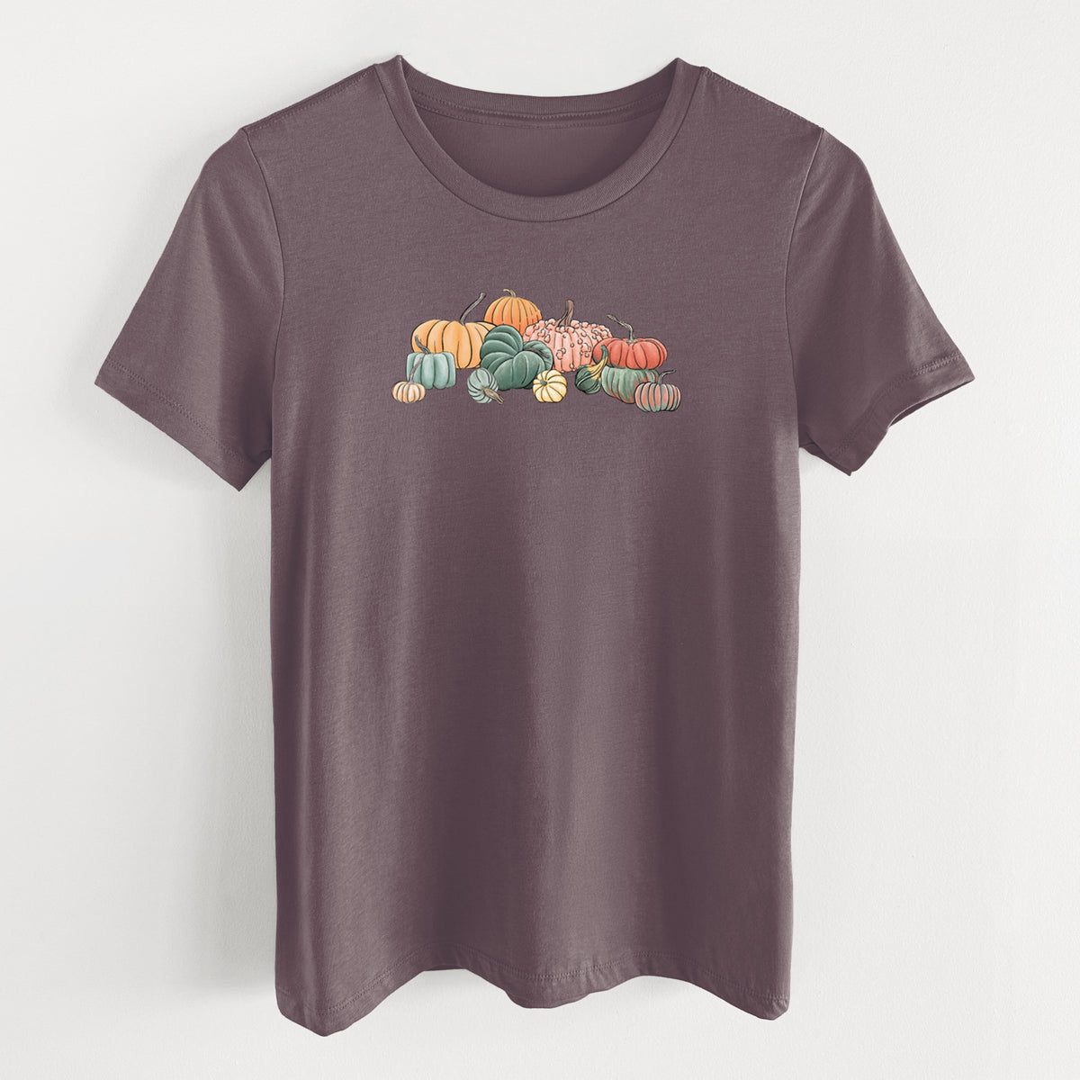 Purple storm women's relaxed fit cotton t-shirt laid flat, printed with a full-color illustration of a pile of pumpkins and gourds in orange, green and white.