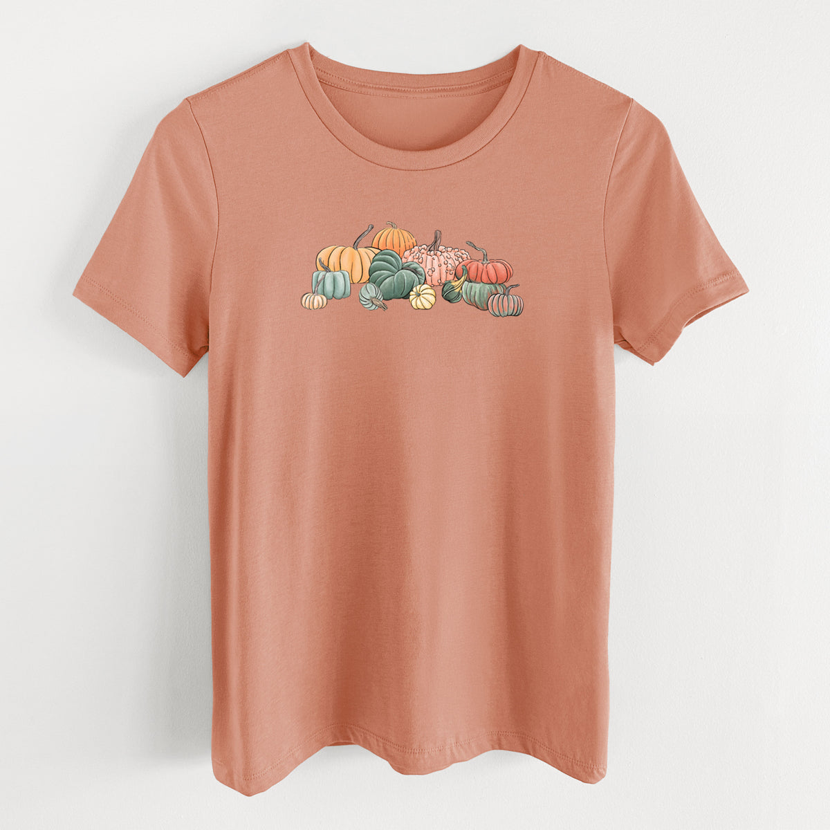 Terracotta orange women's relaxed fit cotton t-shirt laid flat, printed with a full-color illustration of a pile of pumpkins and gourds in orange, green and white.