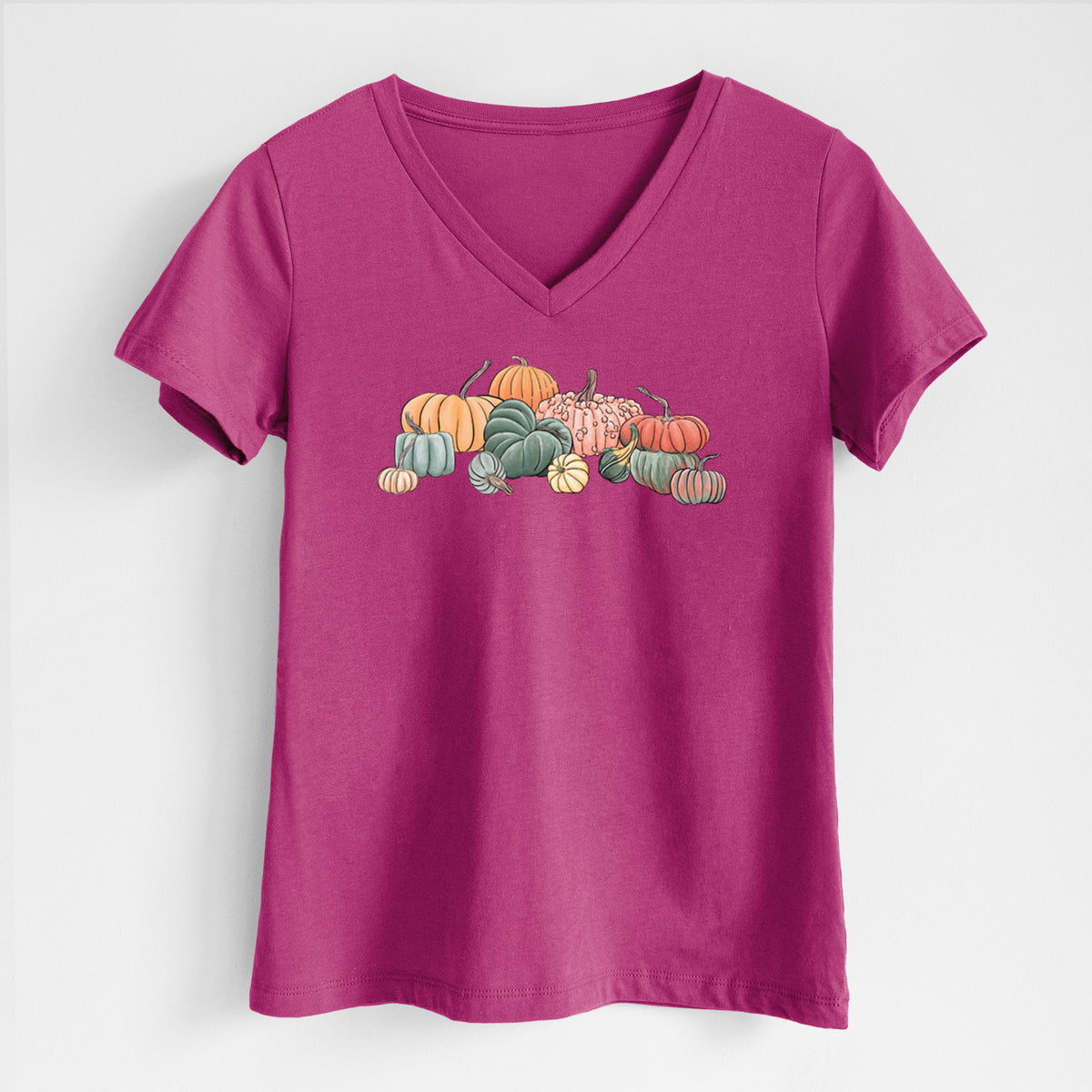 Berry pink women's relaxed fit cotton V-neck t-shirt laid flat, printed with a full-color illustration of a pile of pumpkins and gourds in orange, green and white.