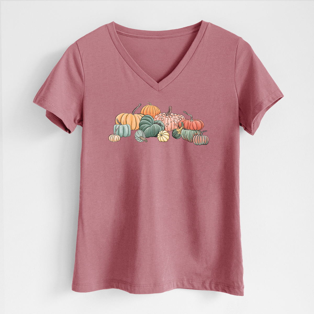 Mauve pink women's relaxed fit cotton V-neck t-shirt laid flat, printed with a full-color illustration of a pile of pumpkins and gourds in orange, green and white.
