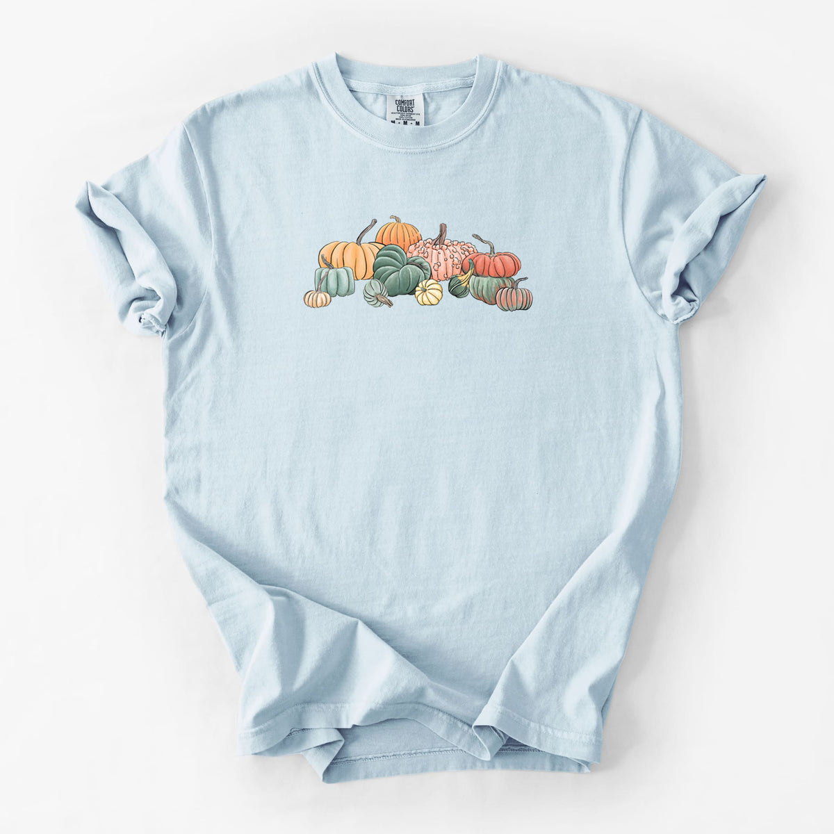 Chambray blue Comfort Colors t-shirt laid flat, printed with a full-color illustration of a pile of pumpkins and gourds in orange, green and white.