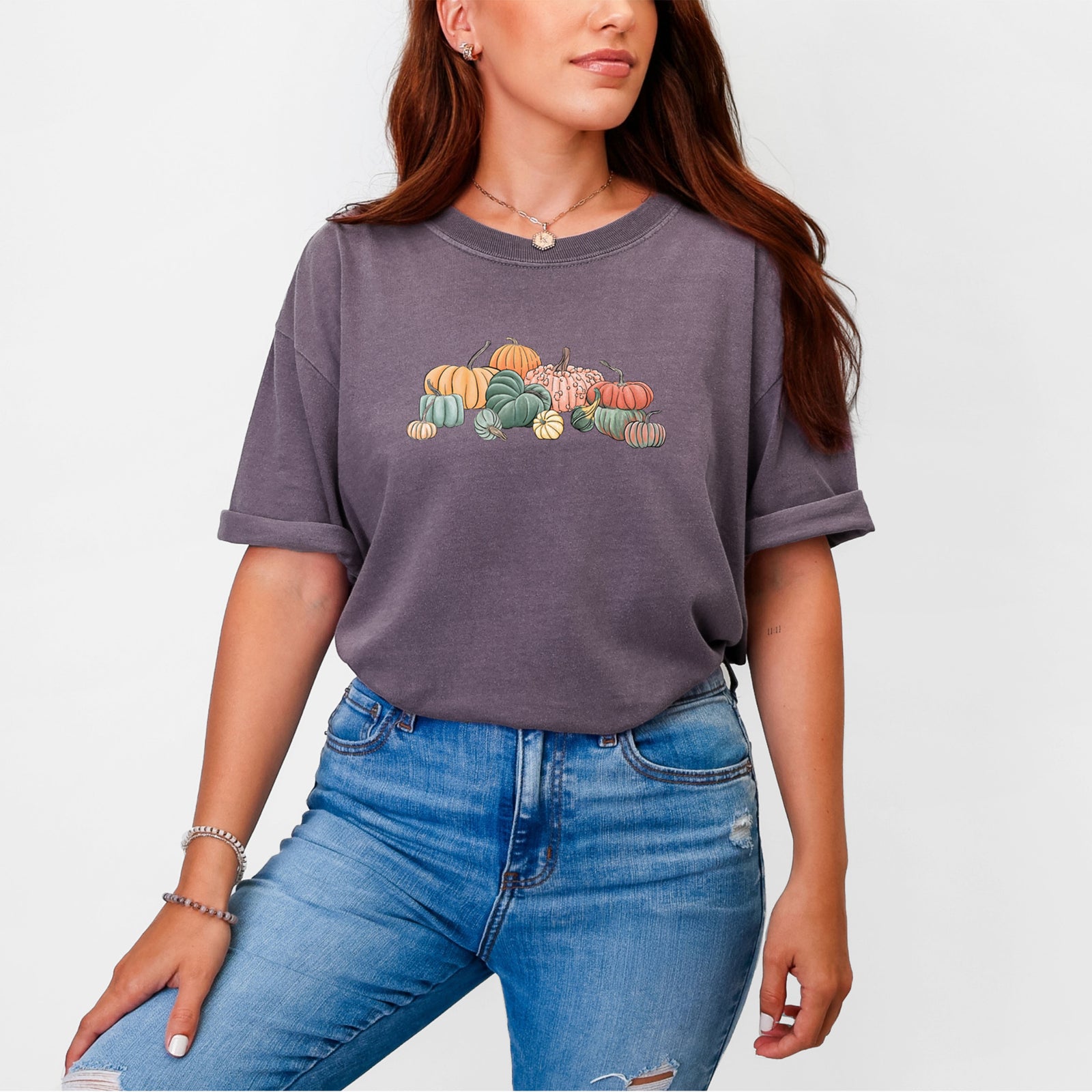 Blue jean Comfort Colors t-shirt laid flat, printed with a full-color illustration of a pile of pumpkins and gourds in orange, green and white.