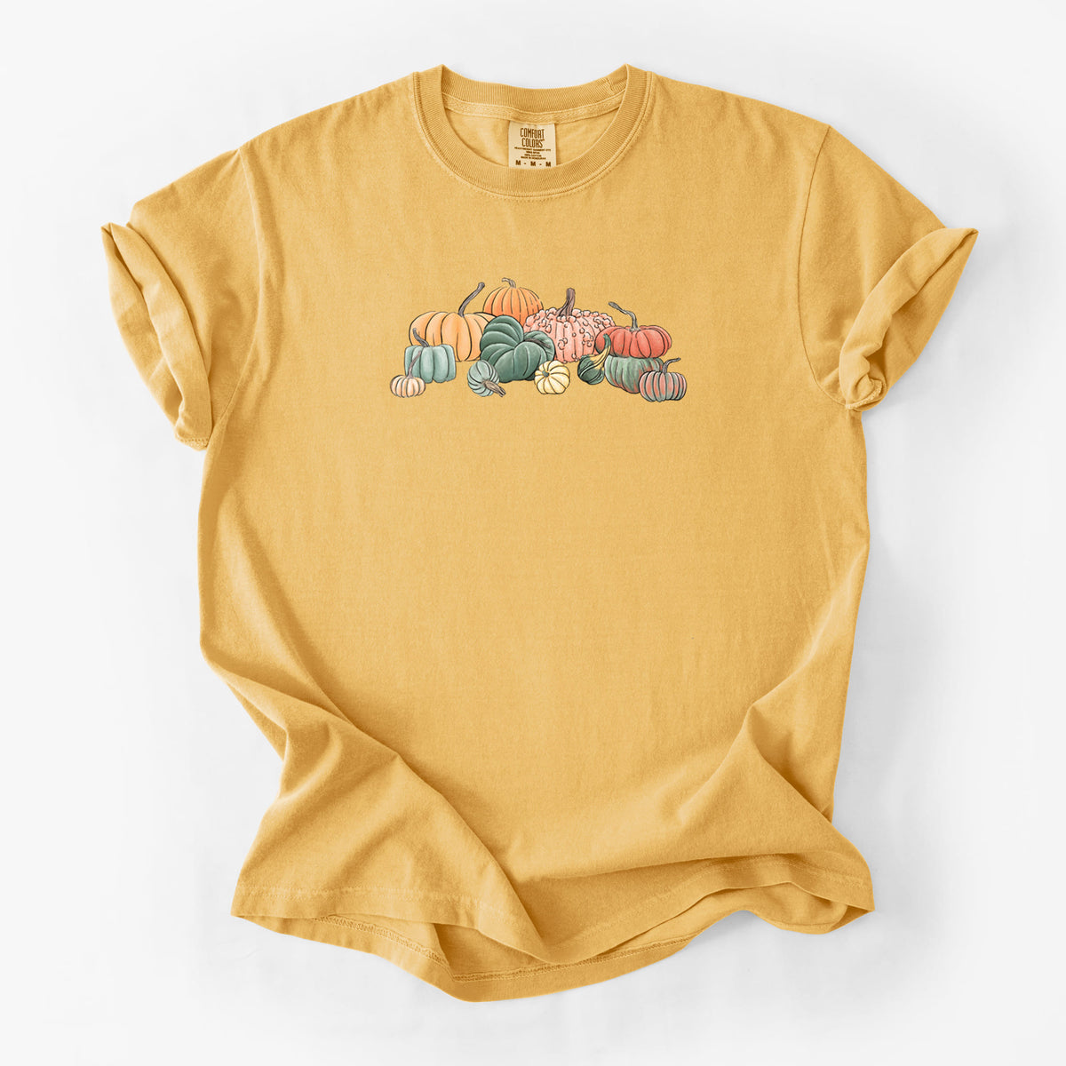 Golden wheat yellow Comfort Colors t-shirt laid flat, printed with a full-color illustration of a pile of pumpkins and gourds in orange, green and white.