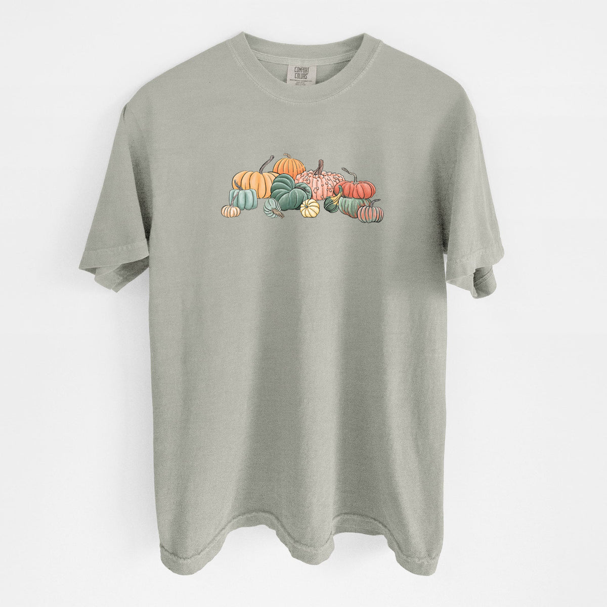 Sandstone beige Comfort Colors t-shirt laid flat, printed with a full-color illustration of a pile of pumpkins and gourds in orange, green and white.