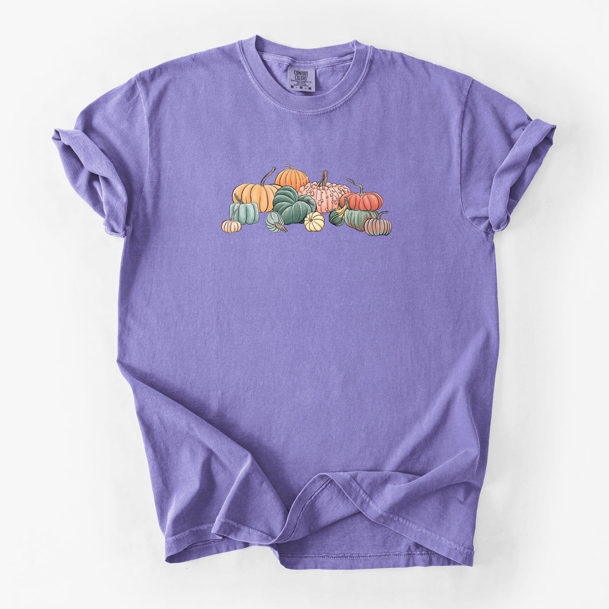 Violet purple Comfort Colors t-shirt laid flat, printed with a full-color illustration of a pile of pumpkins and gourds in orange, green and white.