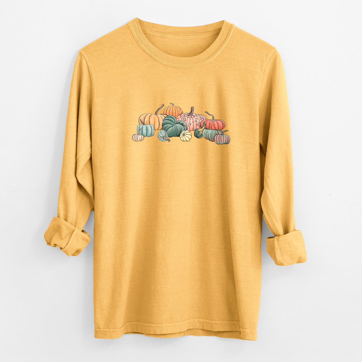 Golden wheat yellow Comfort Colors long sleeve shirt laid flat with the cuffs rolled, printed with a full-color illustration of a pile of pumpkins and gourds in orange, green and white.
