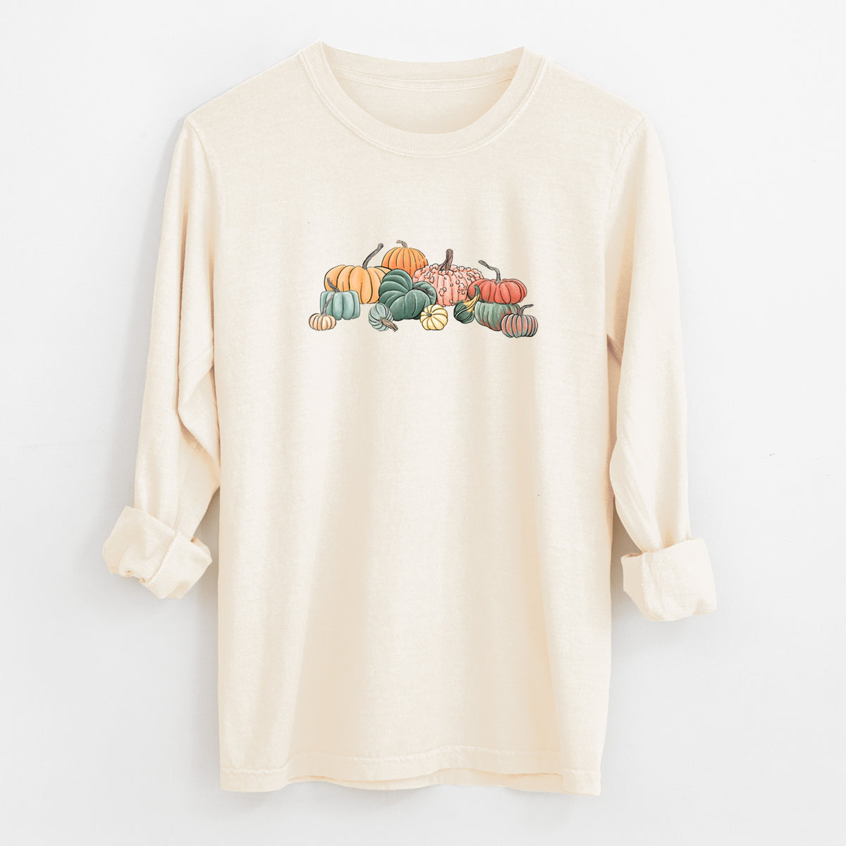 Ivory Comfort Colors long sleeve shirt laid flat with the cuffs rolled, printed with a full-color illustration of a pile of pumpkins and gourds in orange, green and white.