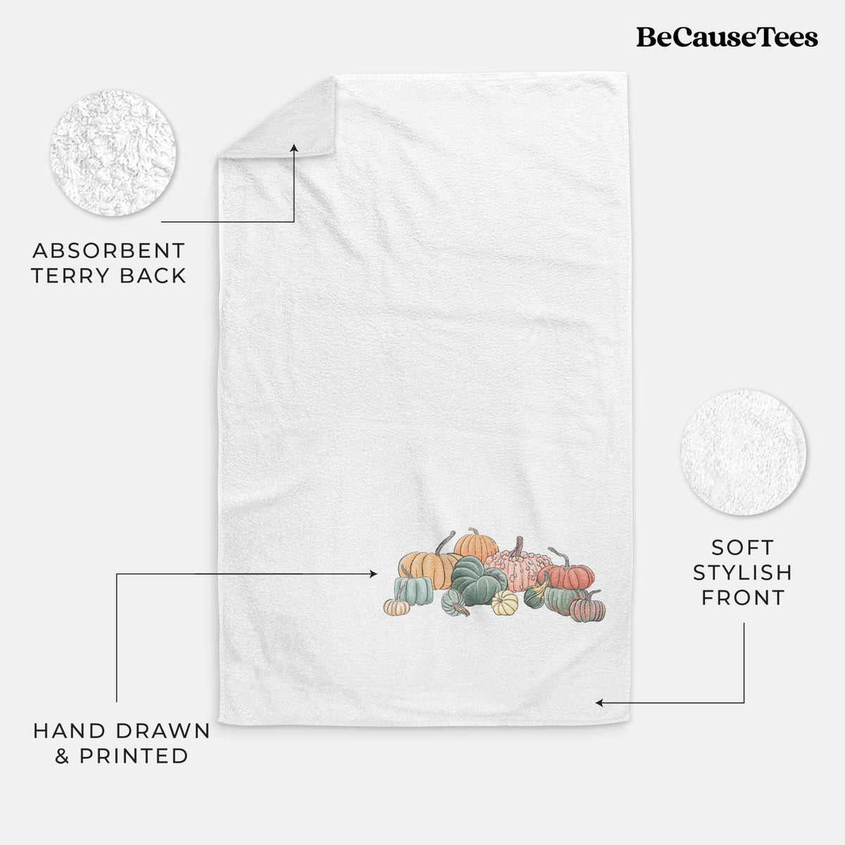 White hand towel printed with a full-color illustration of a pile of pumpkins and gourds in orange, green and white.