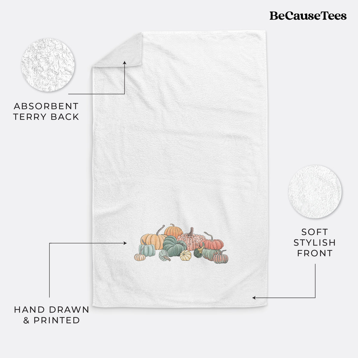 White hand towel printed with a full-color illustration of a pile of pumpkins and gourds in orange, green and white.