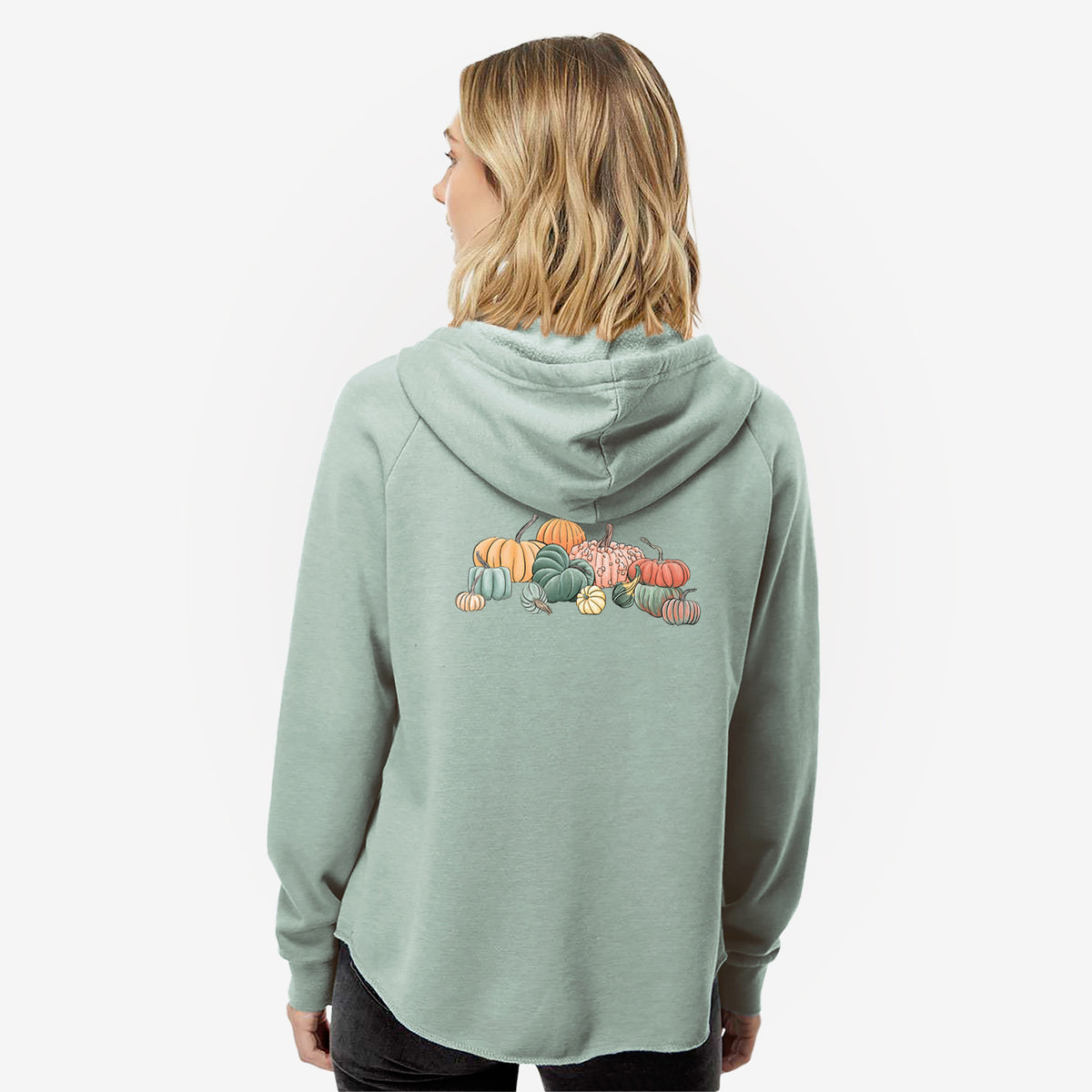 Woman wearing a sage green women's Cali Wave zip-up sweatshirt printed with a full-color illustration of a pile of pumpkins and gourds in orange, green and white, seen from behind.