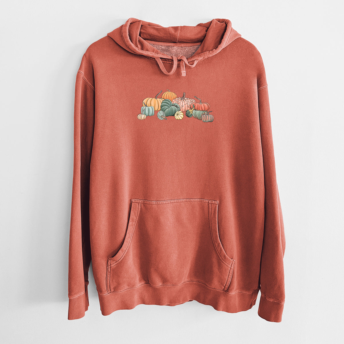 Amber orange pigment dyed hoodie laid flat, printed with a full-color illustration of a pile of pumpkins and gourds in orange, green and white.