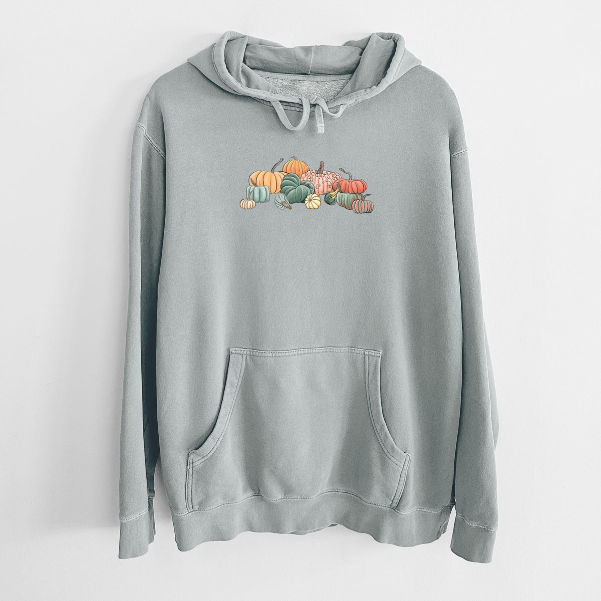 Sage green pigment dyed hoodie laid flat, printed with a full-color illustration of a pile of pumpkins and gourds in orange, green and white.