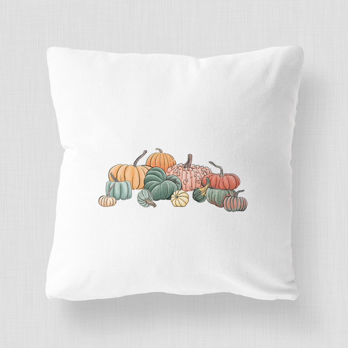 White pillow cover printed with a full-color illustration of a pile of pumpkins and gourds in orange, green and white.