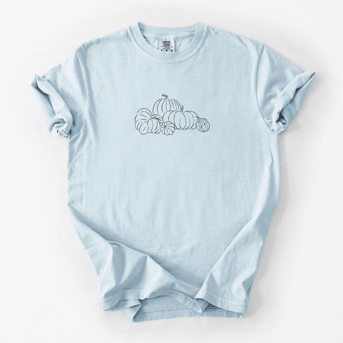 Chambray blue Comfort Colors t-shirt laid flat, printed with a black ink line drawing of a pile of pumpkins.