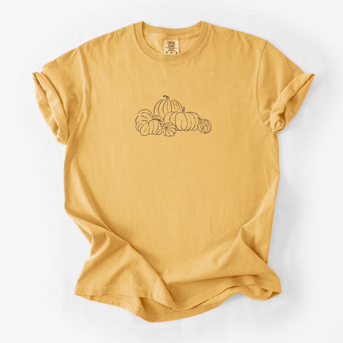 Golden wheat yellow Comfort Colors t-shirt laid flat, printed with a black ink line drawing of a pile of pumpkins.