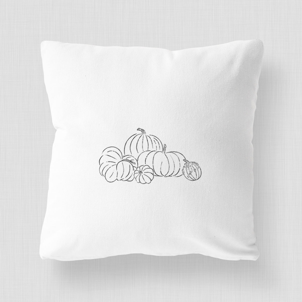 White pillow cover printed with a black ink line drawing of a pile of pumpkins.
