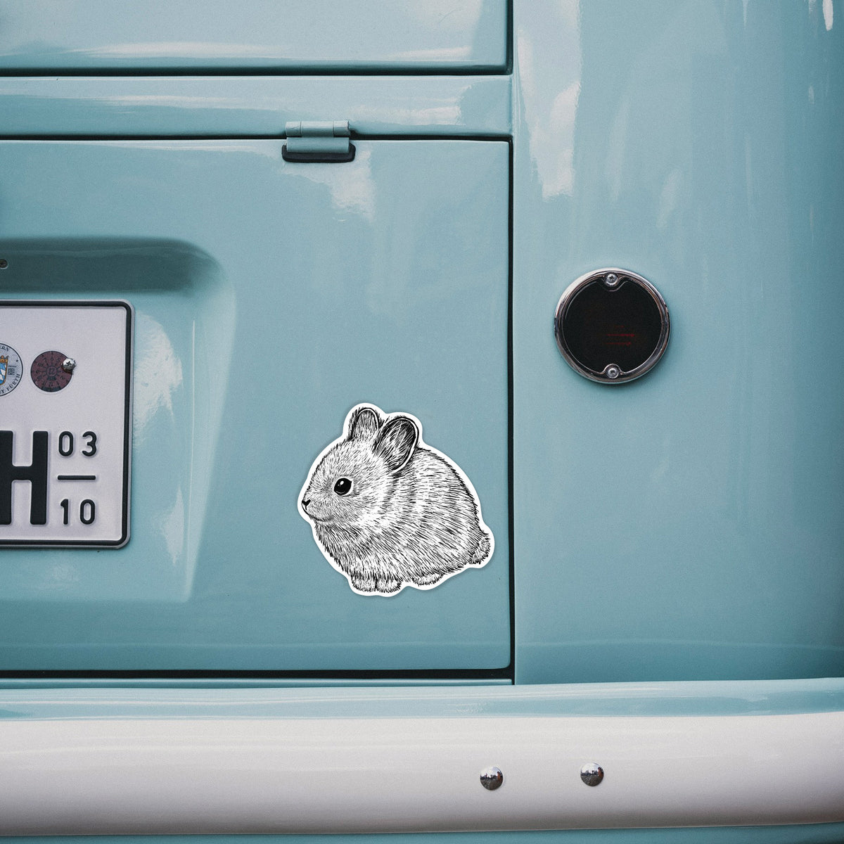 4 inch vinyl decal of a detailed black ink illustration of a round, fluffy pygmy rabbit on the back of a van.