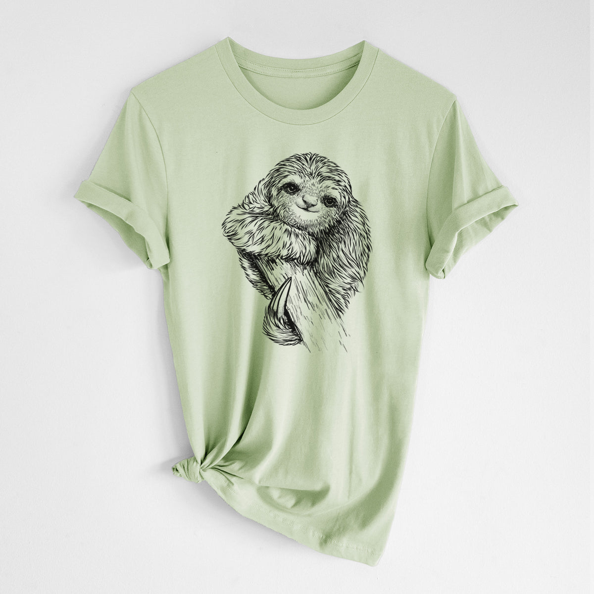 Spring green lightweight cotton t-shirt laid flat with the sleeves rolled, printed with a detailed black ink illustration of a smiling pygmy three-toed sloth hanging from a branch.