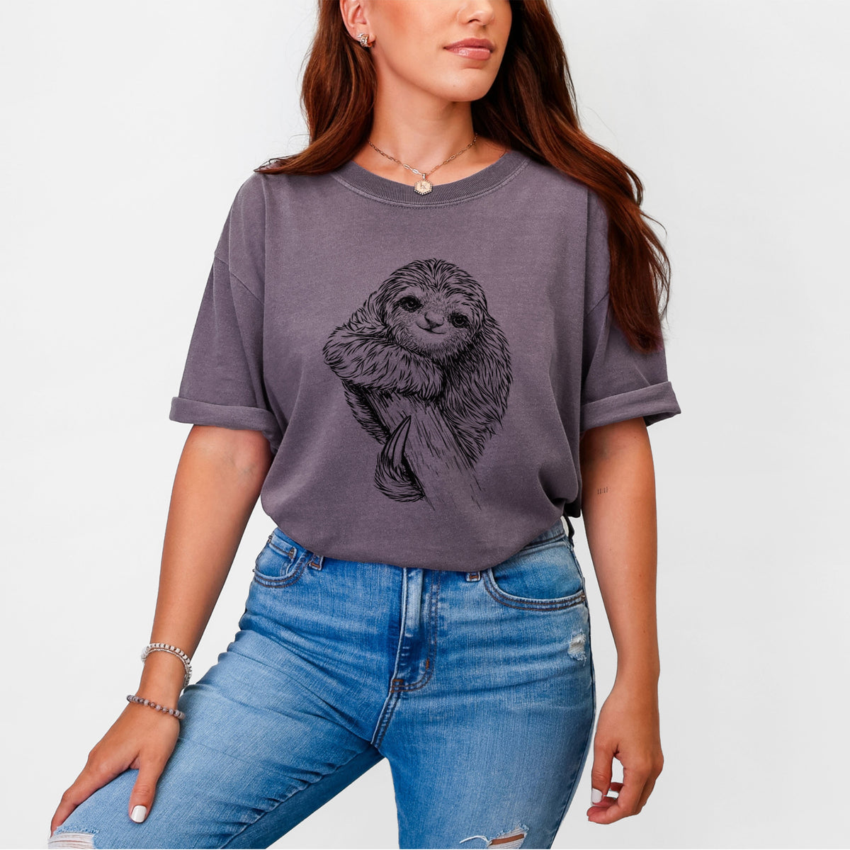 Woman wearing a Comfort Colors t-shirt printed with a detailed black ink illustration of a smiling pygmy three-toed sloth hanging from a branch.