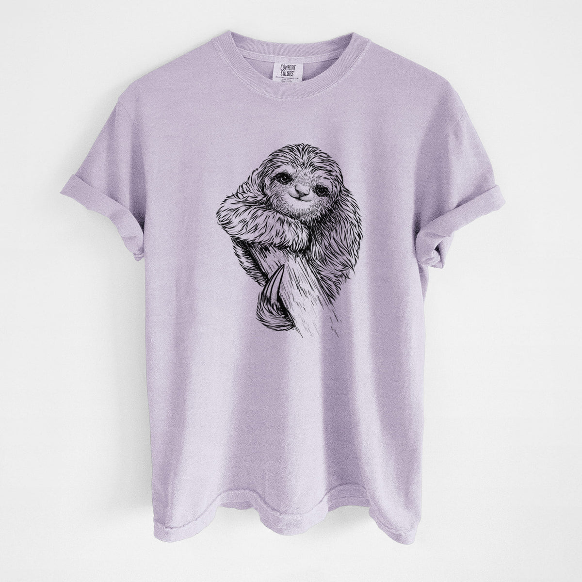 Orchid purple Comfort Colors t-shirt laid flat, printed with a detailed black ink illustration of a smiling pygmy three-toed sloth hanging from a branch.