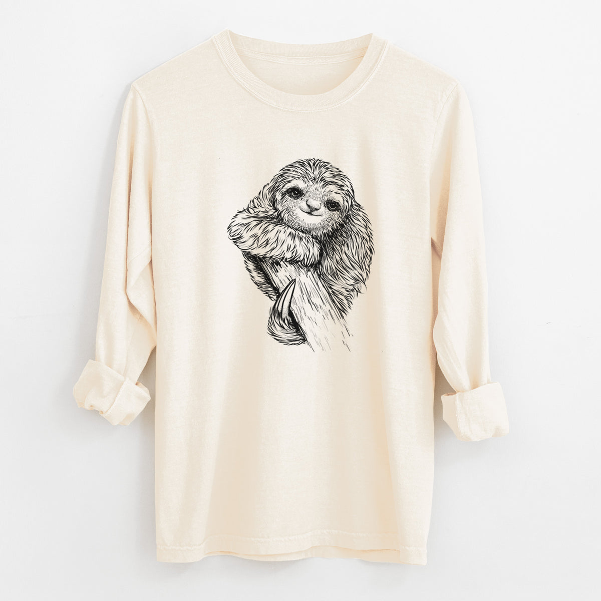 Ivory Comfort Colors long sleeve shirt laid flat with the cuffs rolled, printed with a detailed black ink illustration of a smiling pygmy three-toed sloth hanging from a branch.