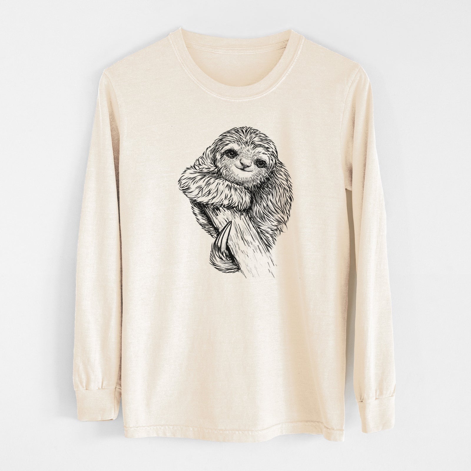 Ivory Comfort Colors long sleeve shirt laid flat, printed with a detailed black ink illustration of a smiling pygmy three-toed sloth hanging from a branch.