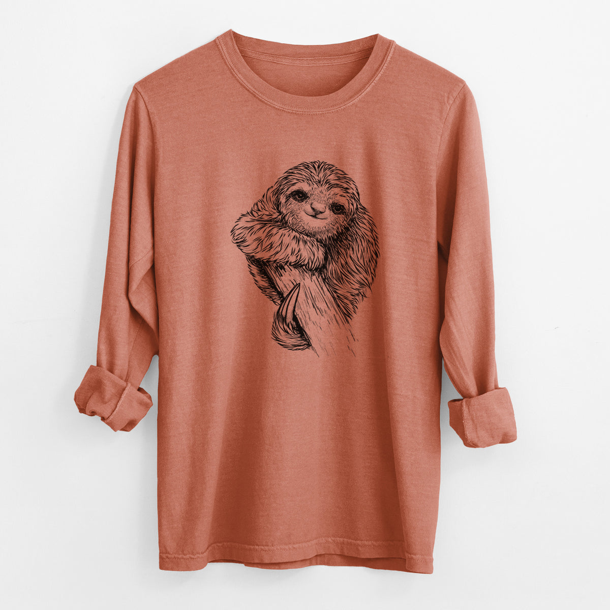 Yam burnt orange Comfort Colors long sleeve shirt laid flat with the cuffs rolled, printed with a detailed black ink illustration of a smiling pygmy three-toed sloth hanging from a branch.