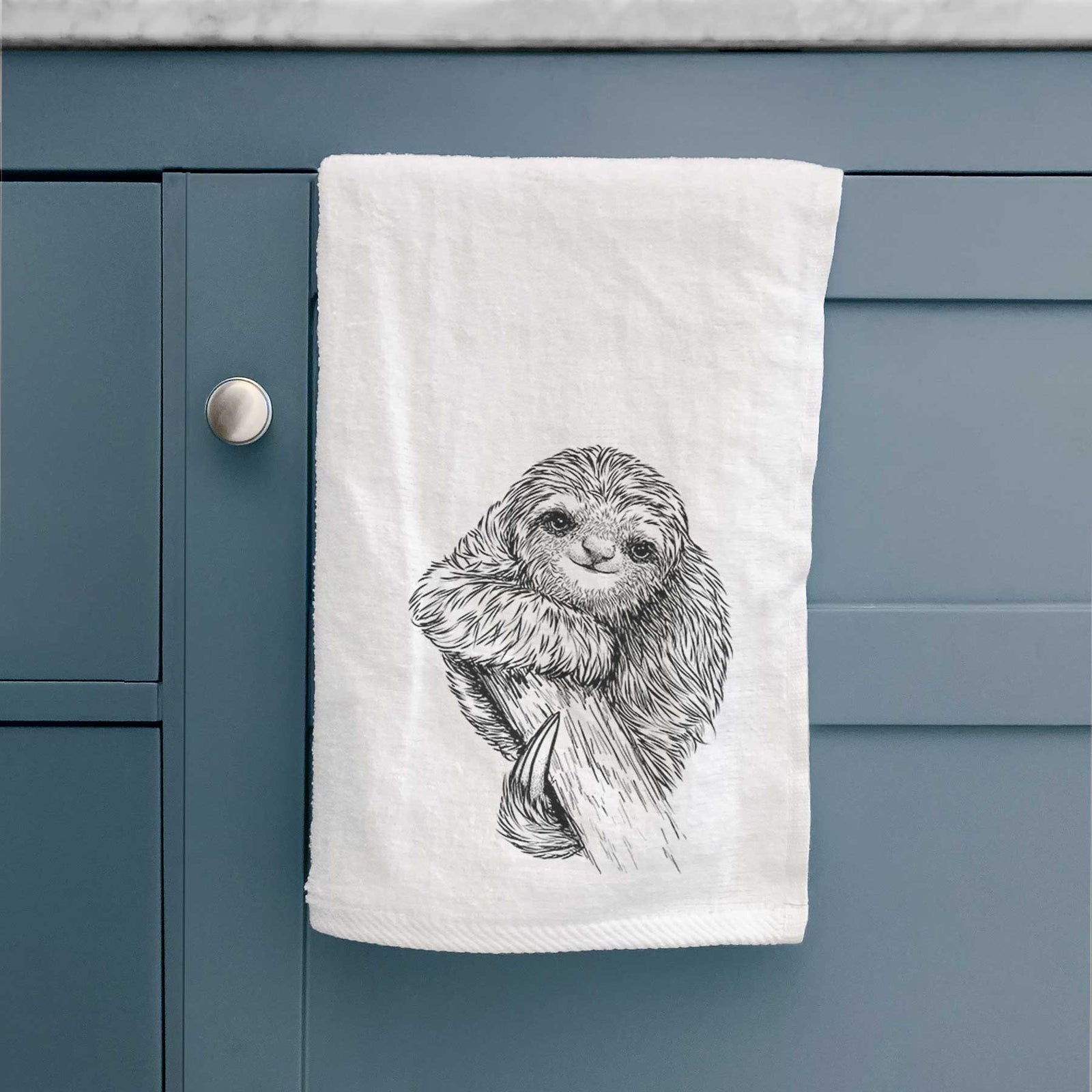 White hand towel printed with a detailed black ink illustration of a smiling pygmy three-toed sloth hanging from a branch.