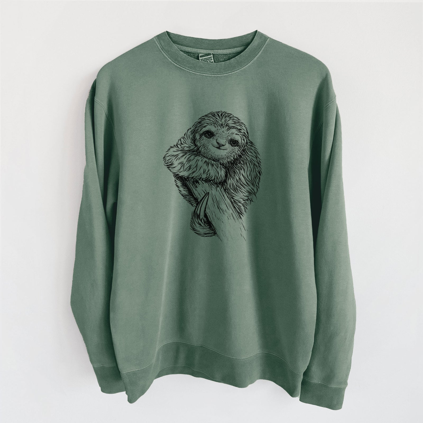 Alpine green pigment dyed crewneck sweatshirt laid flat, printed with a detailed black ink illustration of a smiling pygmy three-toed sloth hanging from a branch.