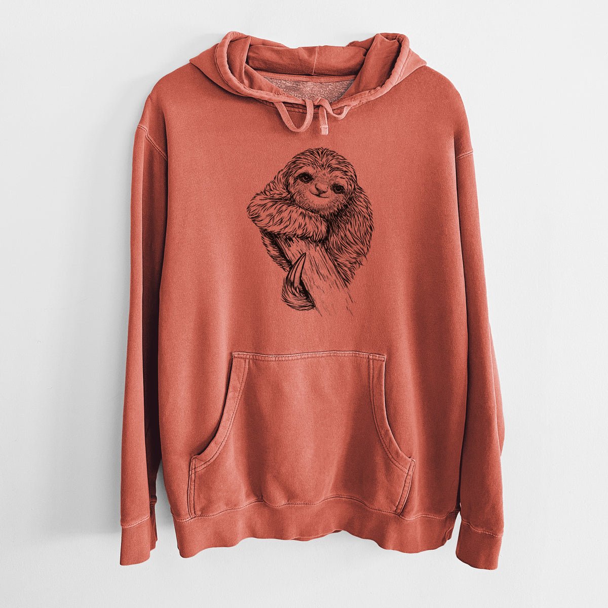 Amber orange pigment dyed hoodie laid flat, printed with a detailed black ink illustration of a smiling pygmy three-toed sloth hanging from a branch.