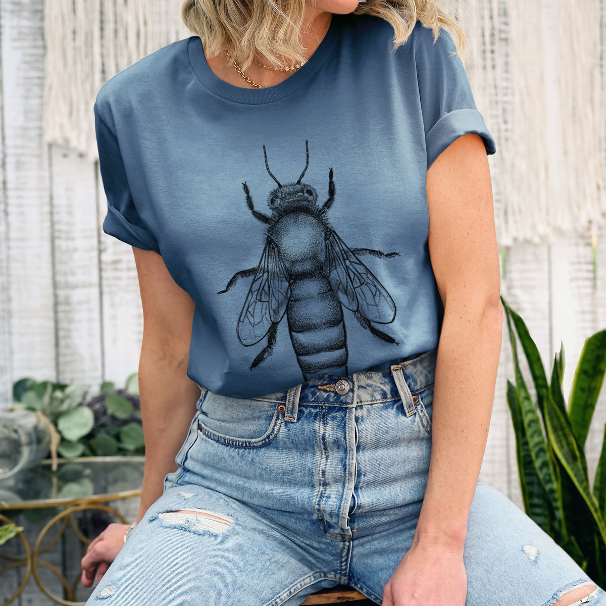 Woman wearing a steel blue lightweight cotton t-shirt printed with a detailed black ink illustration of a queen honey bee, seen from above.