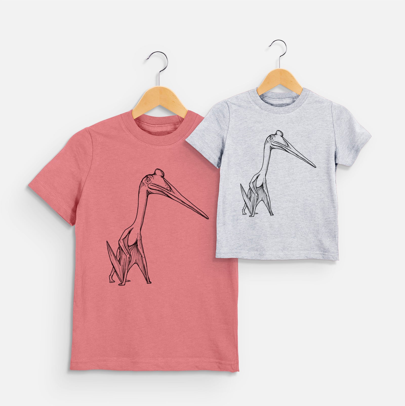 Two youth t-shirts in different colors on hangers, printed with a black ink illustration of a Quetzalcoatlus pterosaur standing on all fours.