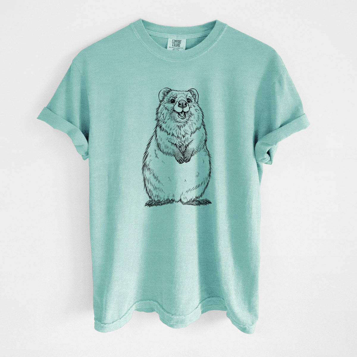 Chalky mint Comfort Colors t-shirt laid flat, printed with a black ink illustration of a smiling quokka sitting upright.