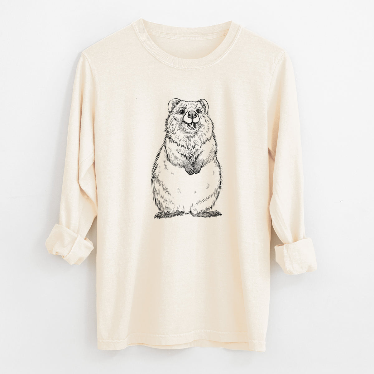 Ivory Comfort Colors long sleeve shirt laid flat with the cuffs rolled, printed with a black ink illustration of a smiling quokka sitting upright.
