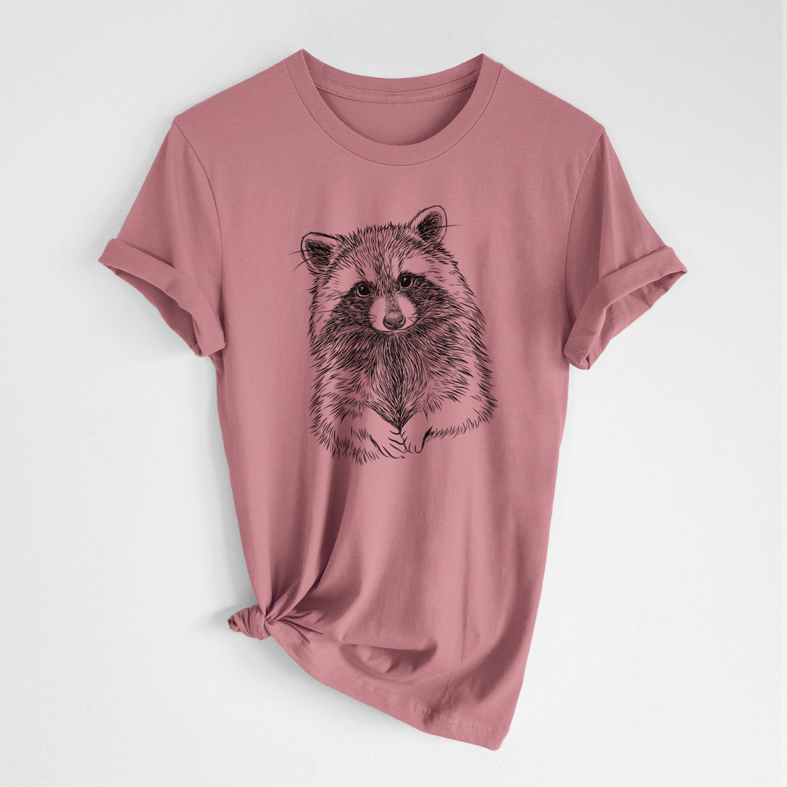 Mauve pink lightweight cotton t-shirt laid flat with the sleeves rolled, printed with a detailed black ink portrait of a raccoon with its front paws resting in front of it.