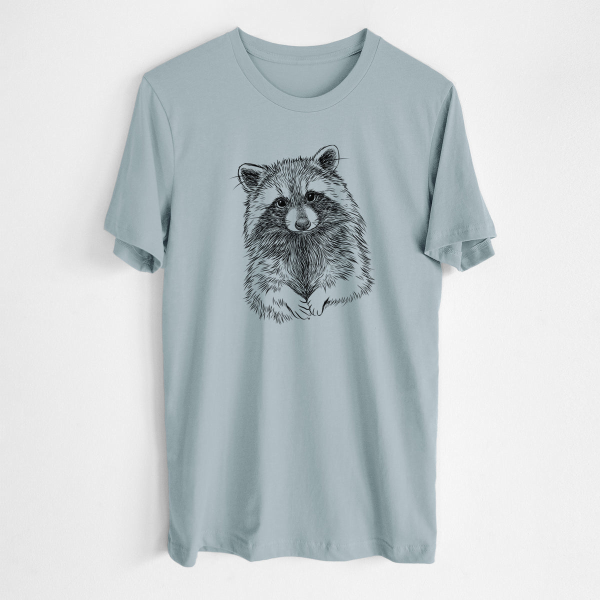 Vintage denim lightweight cotton t-shirt laid flat, printed with a detailed black ink portrait of a raccoon with its front paws resting in front of it.