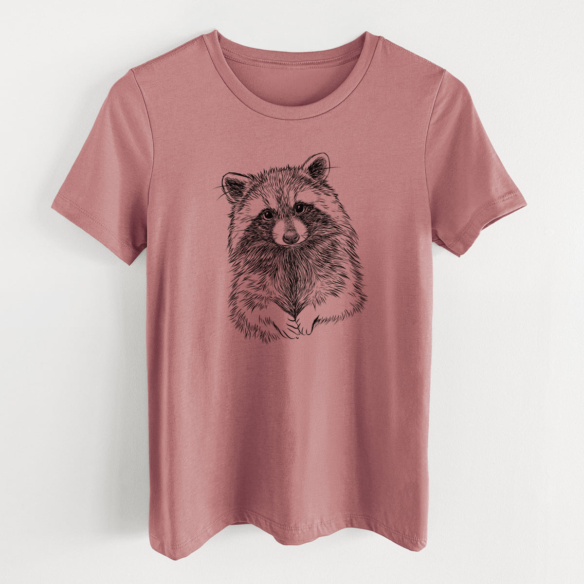 Mauve pink women's relaxed fit cotton t-shirt laid flat, printed with a detailed black ink portrait of a raccoon with its front paws resting in front of it.