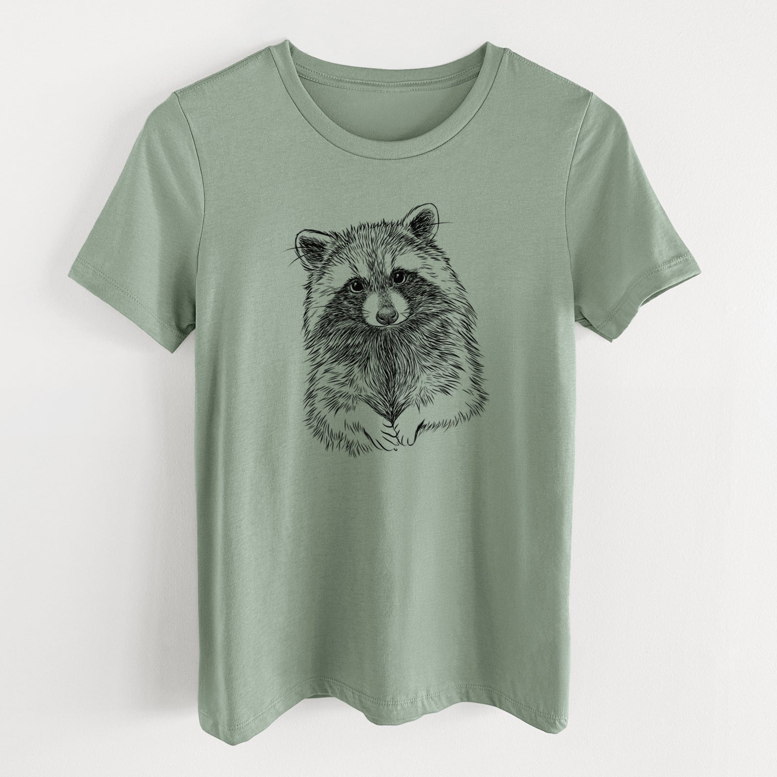 Sage green women's relaxed fit cotton t-shirt laid flat, printed with a detailed black ink portrait of a raccoon with its front paws resting in front of it.