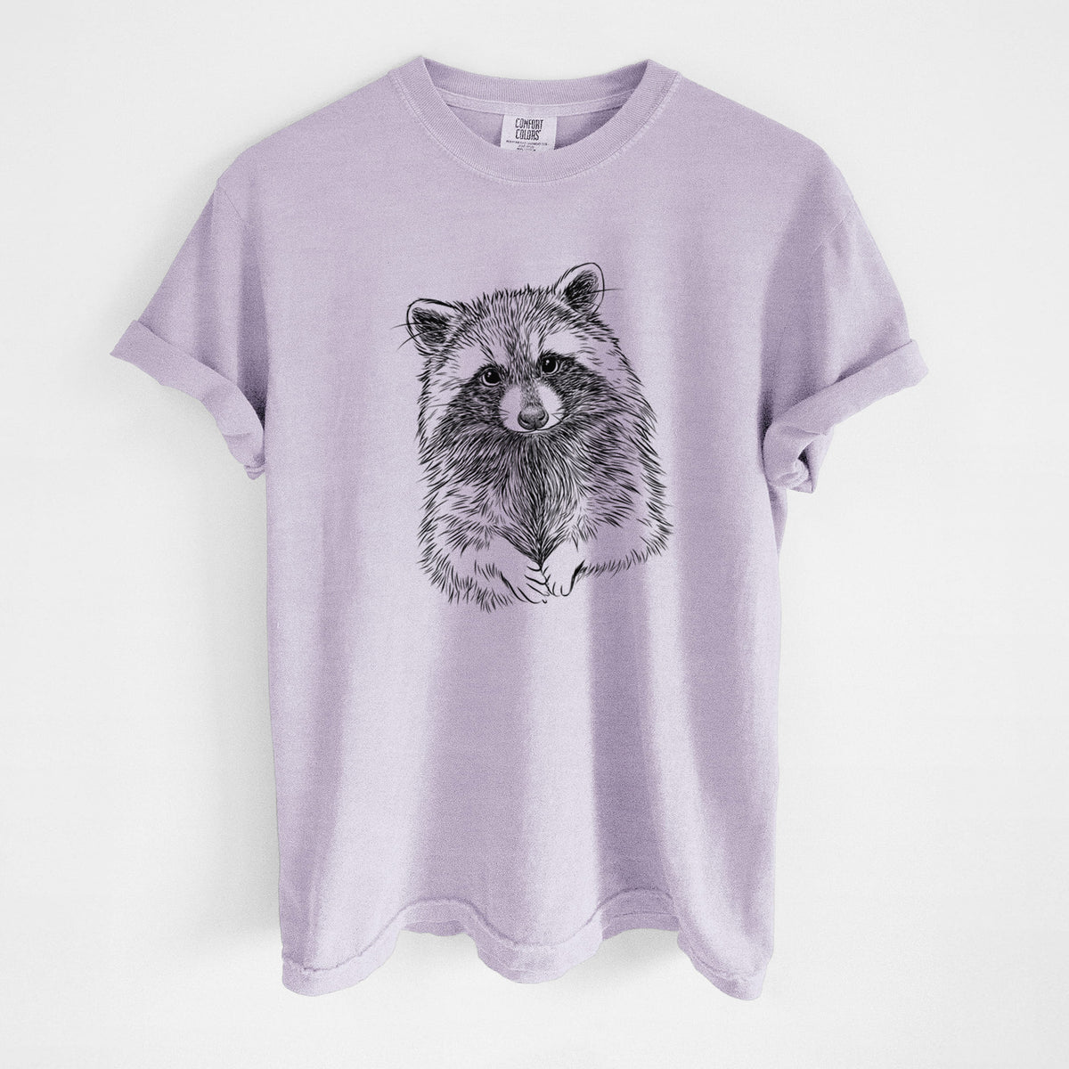 Orchid purple Comfort Colors t-shirt laid flat, printed with a detailed black ink portrait of a raccoon with its front paws resting in front of it.