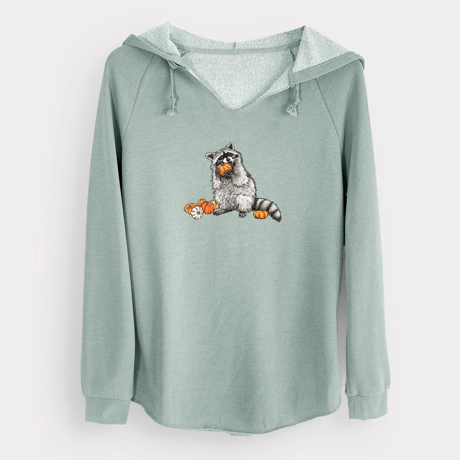 Sage green women's Cali Wave hooded sweatshirt laid flat, printed with a black ink raccoon eating a small orange pumpkin, with more pumpkins beside it.