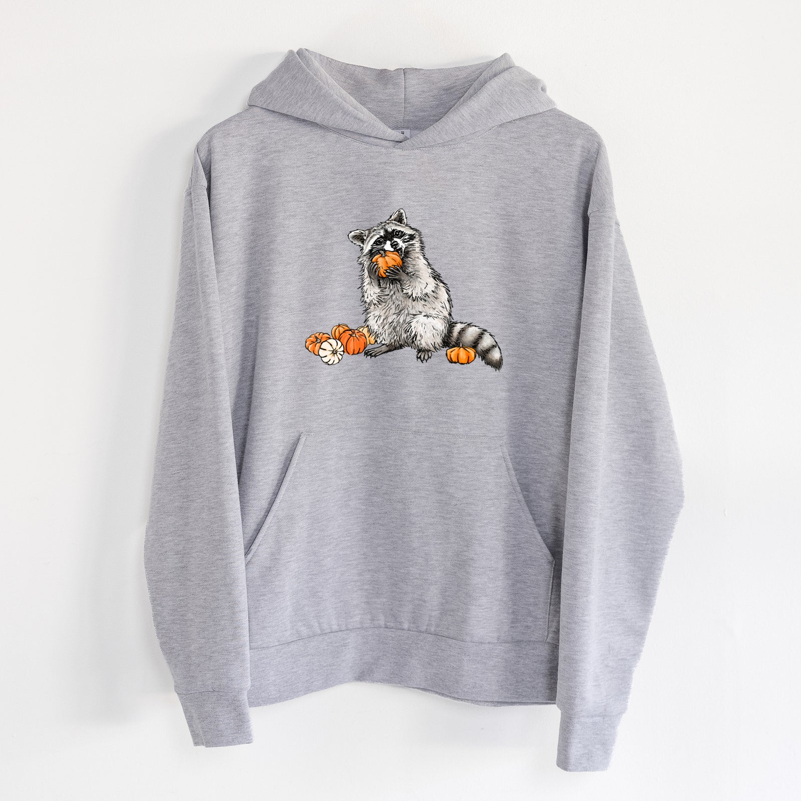 Raccoon Pumpkin Bandit - Statement Midweight Hoodie in Heather Grey, hanging on a white wall, with a front kangaroo pocket and no drawcords.