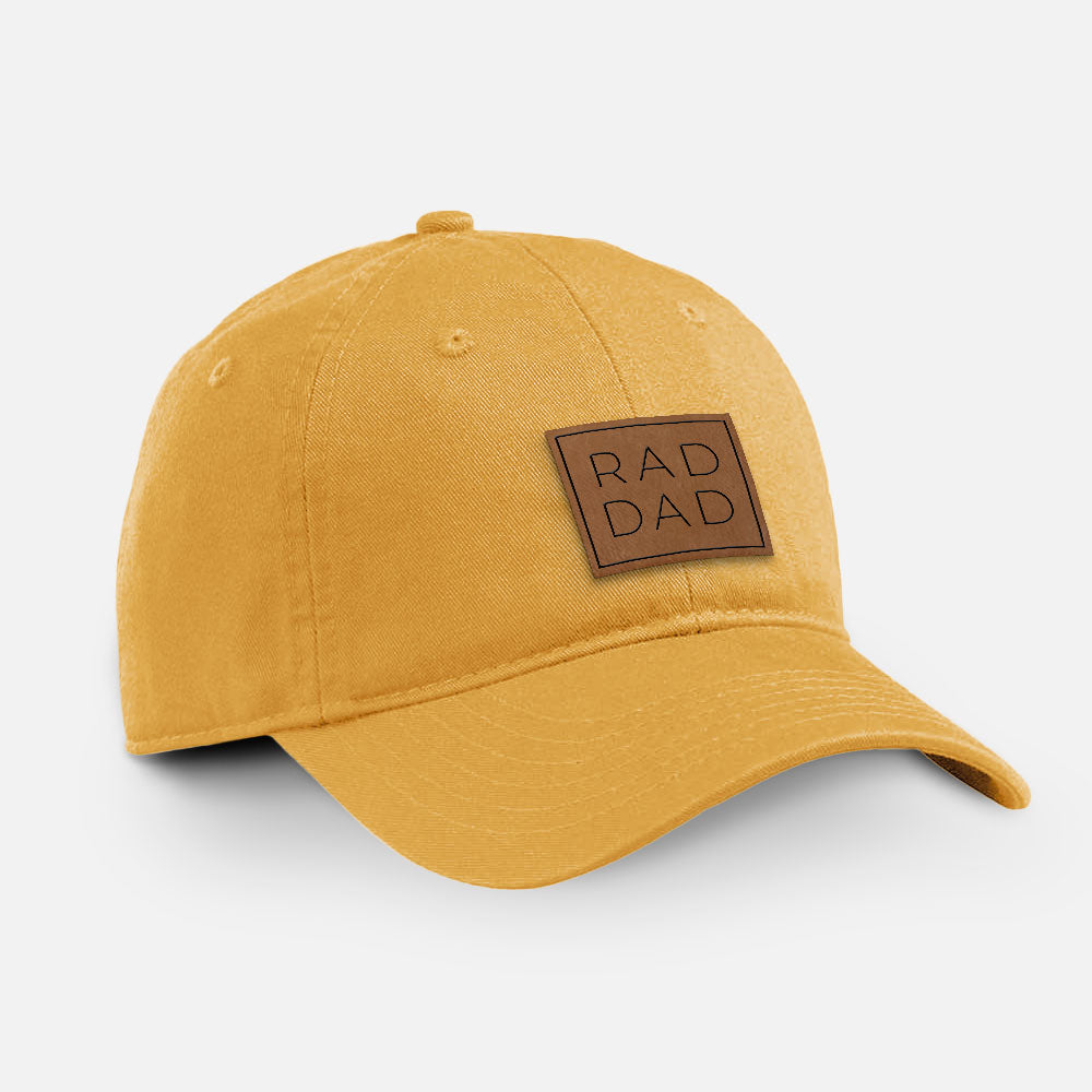 Beehive yellow cotton baseball hat with a brown leather patch engraved with the words RAD DAD stacked in a square on the front.