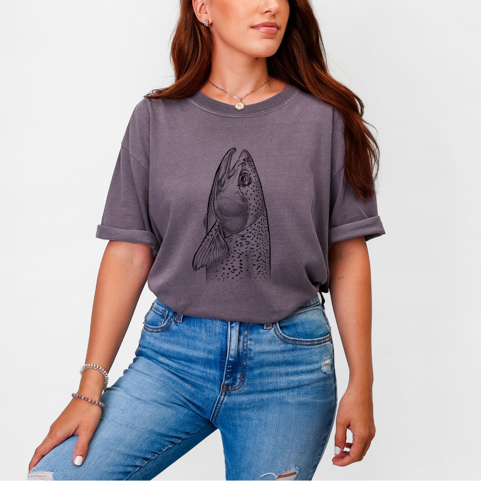 Blue jean Comfort Colors t-shirt laid flat, printed with a detailed black ink illustration of a rainbow trout's head pointing upward, showing its spotted scales.