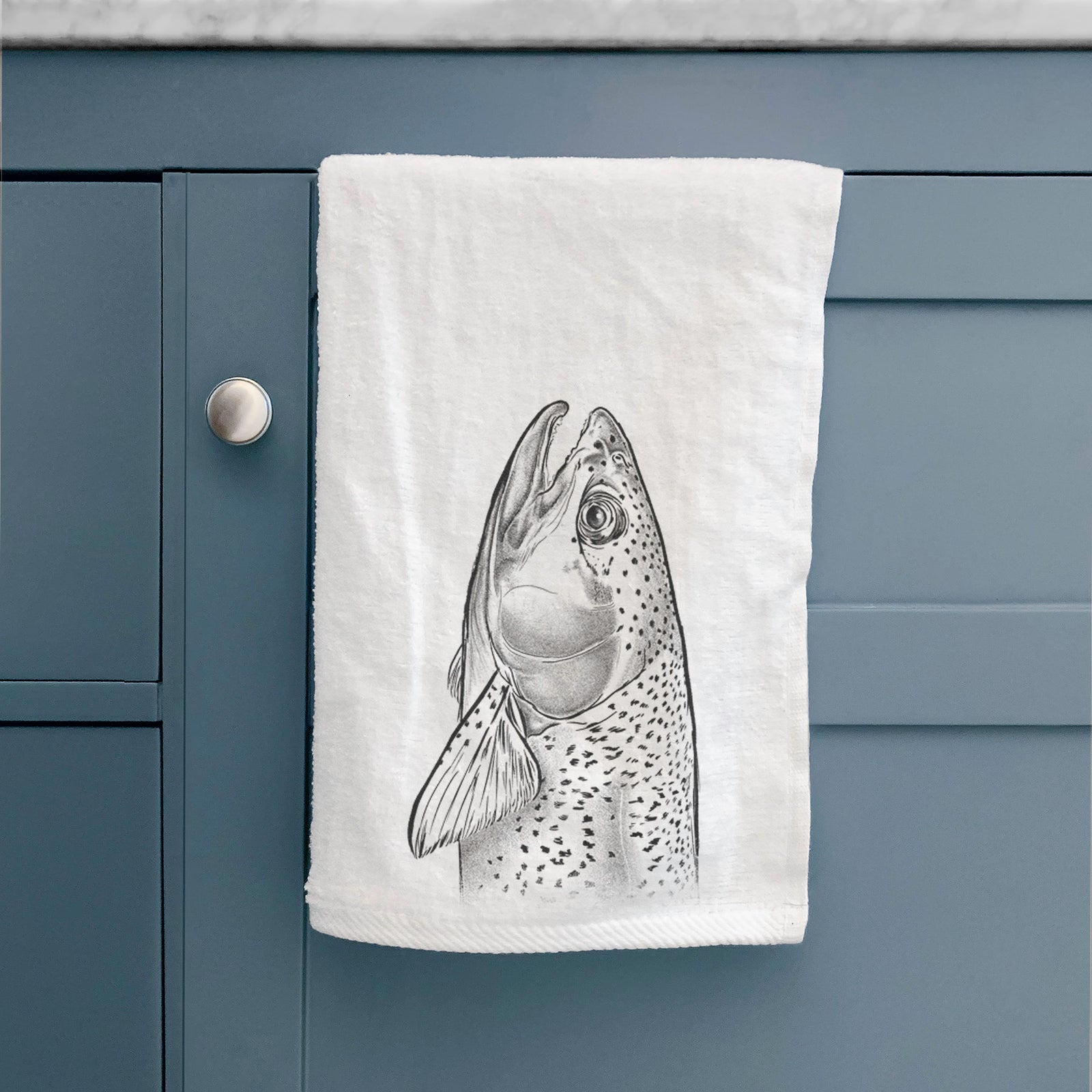 White hand towel printed with a detailed black ink illustration of a rainbow trout's head pointing upward, showing its spotted scales.