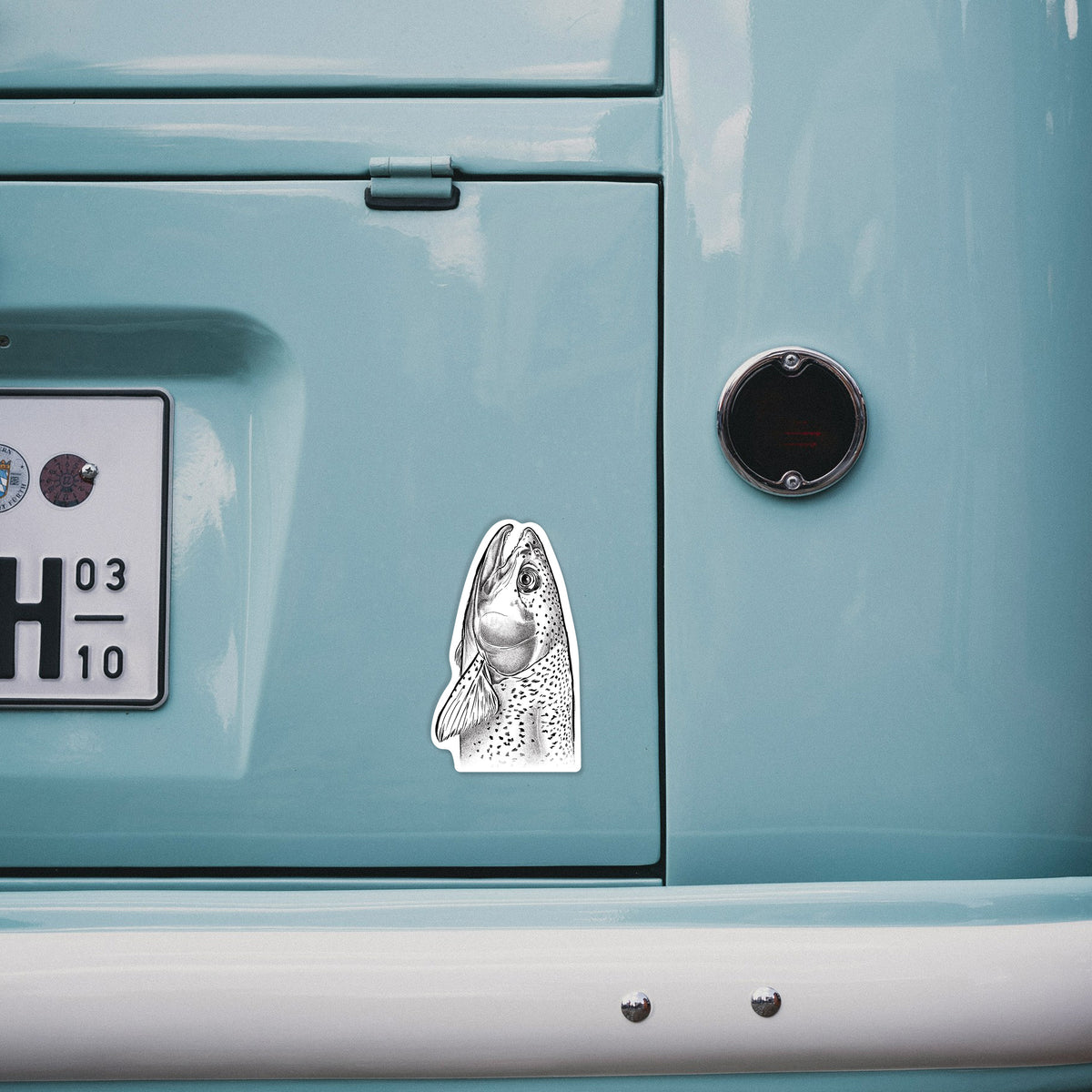 4 inch vinyl decal of a detailed black ink illustration of a rainbow trout's head pointing upward, showing its spotted scales on the back of a van.