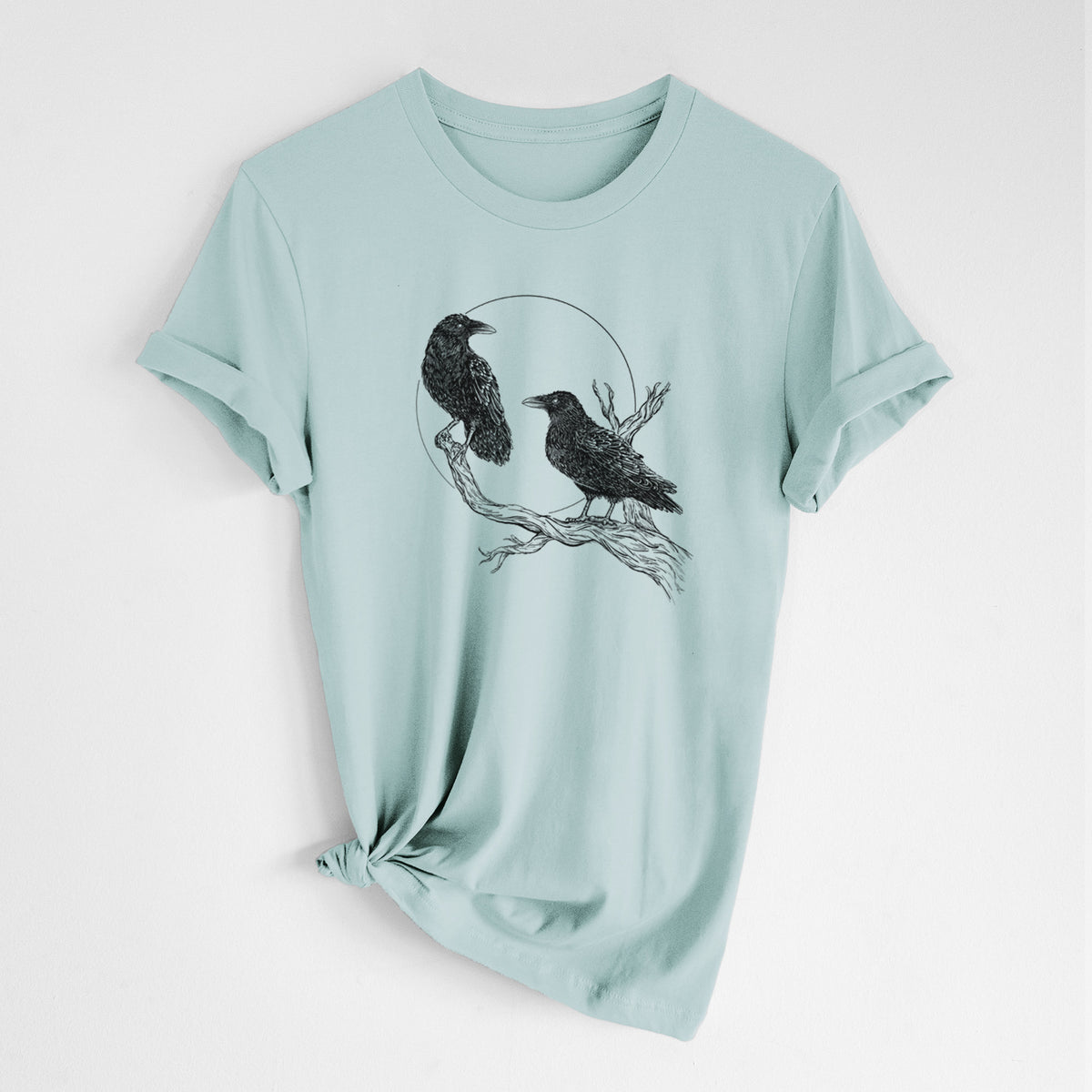 Dusty blue lightweight cotton t-shirt laid flat with the sleeves rolled, printed with a black ink illustration of two ravens perched on a branch in front of a full moon.