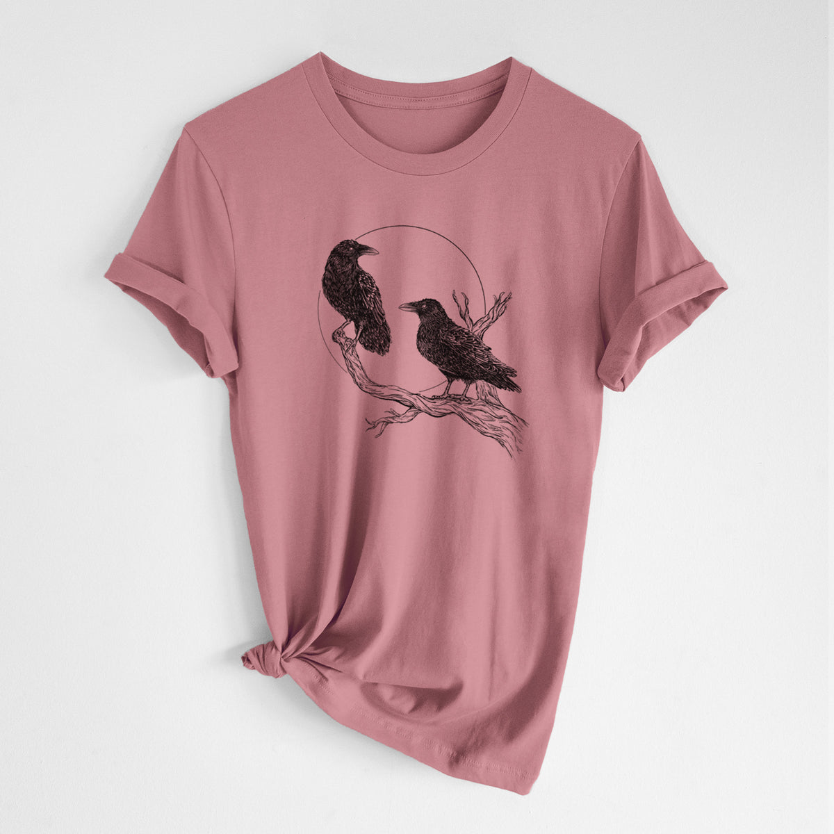 Mauve pink lightweight cotton t-shirt laid flat with the sleeves rolled, printed with a black ink illustration of two ravens perched on a branch in front of a full moon.