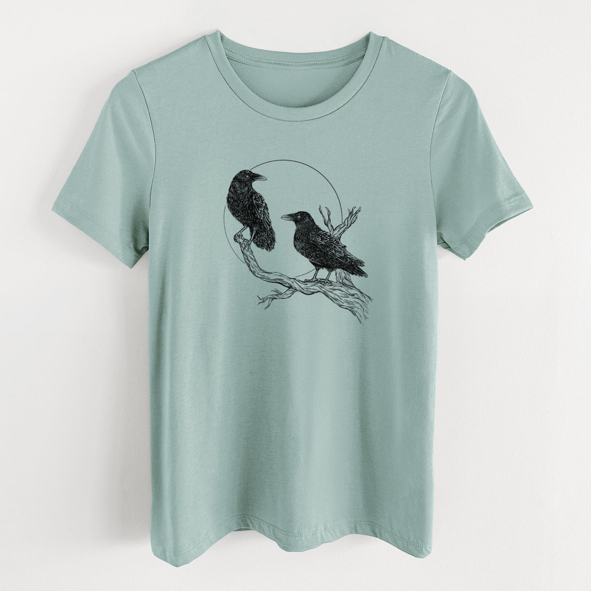 Dusty blue women's relaxed fit cotton t-shirt laid flat, printed with a black ink illustration of two ravens perched on a branch in front of a full moon.