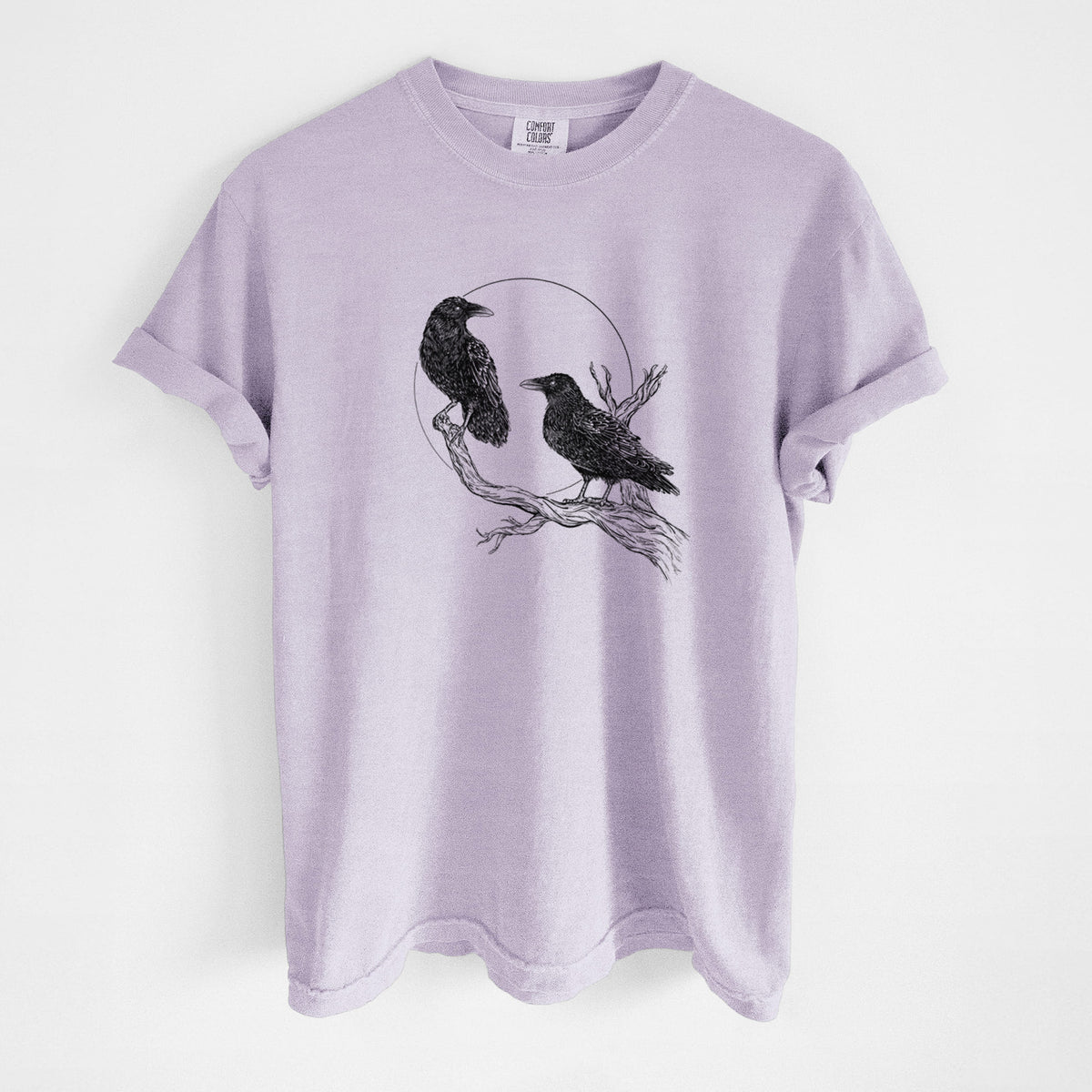 Orchid purple Comfort Colors t-shirt laid flat, printed with a black ink illustration of two ravens perched on a branch in front of a full moon.